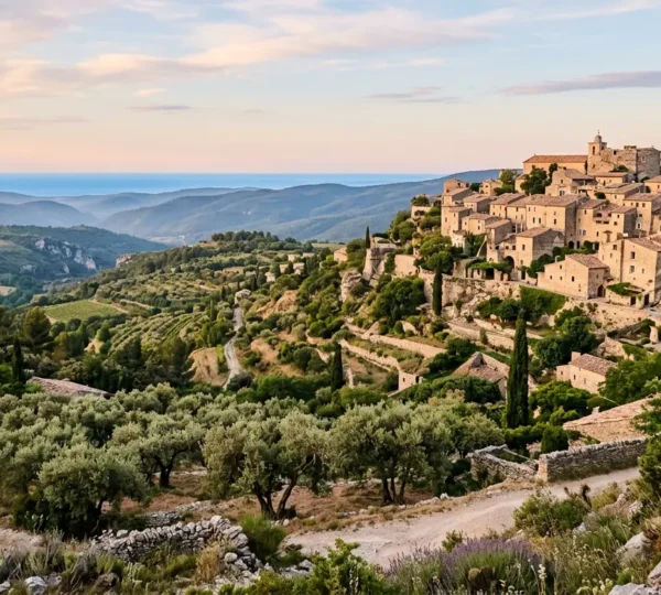 Vue panoramique d'un village perché de l'arrière-pays niçois entouré de collines verdoyantes et de la mer Méditerranée en arrière-plan