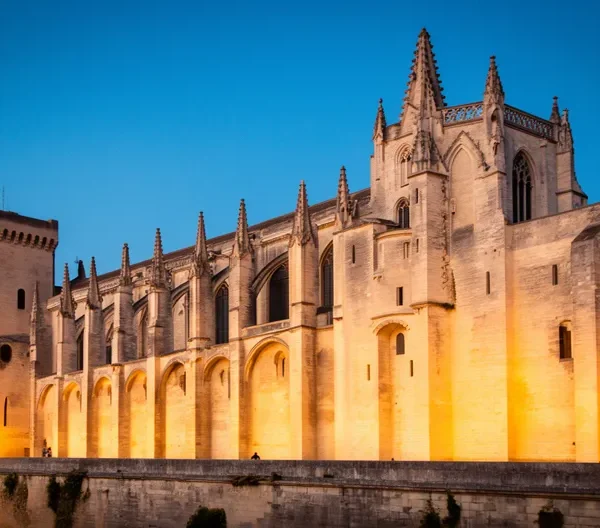 Vue atmosphérique de la Cité des Papes d'Avignon au crépuscule, mêlant architecture gothique et lumières dorées