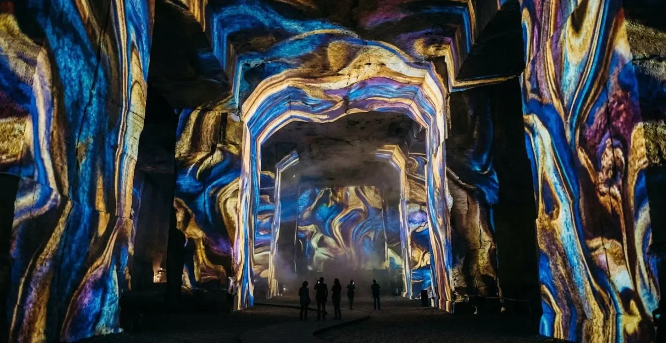 Intérieur des Carrières de Lumières avec projections colorées sur les parois rocheuses