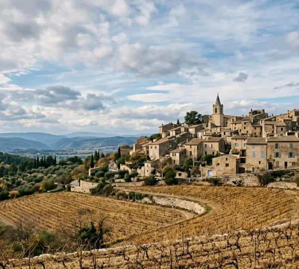 Village provençal en novembre avec vignes dorées, ciel automnal et ambiance sereine hors saison