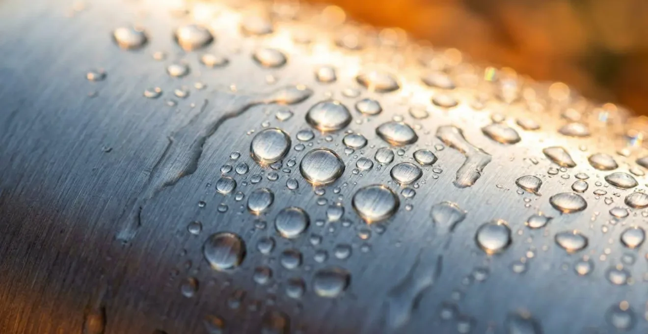 Gros plan macro sur des gouttelettes de condensation sur une gourde métallique avec arrière-plan flou de garrigue provençale
